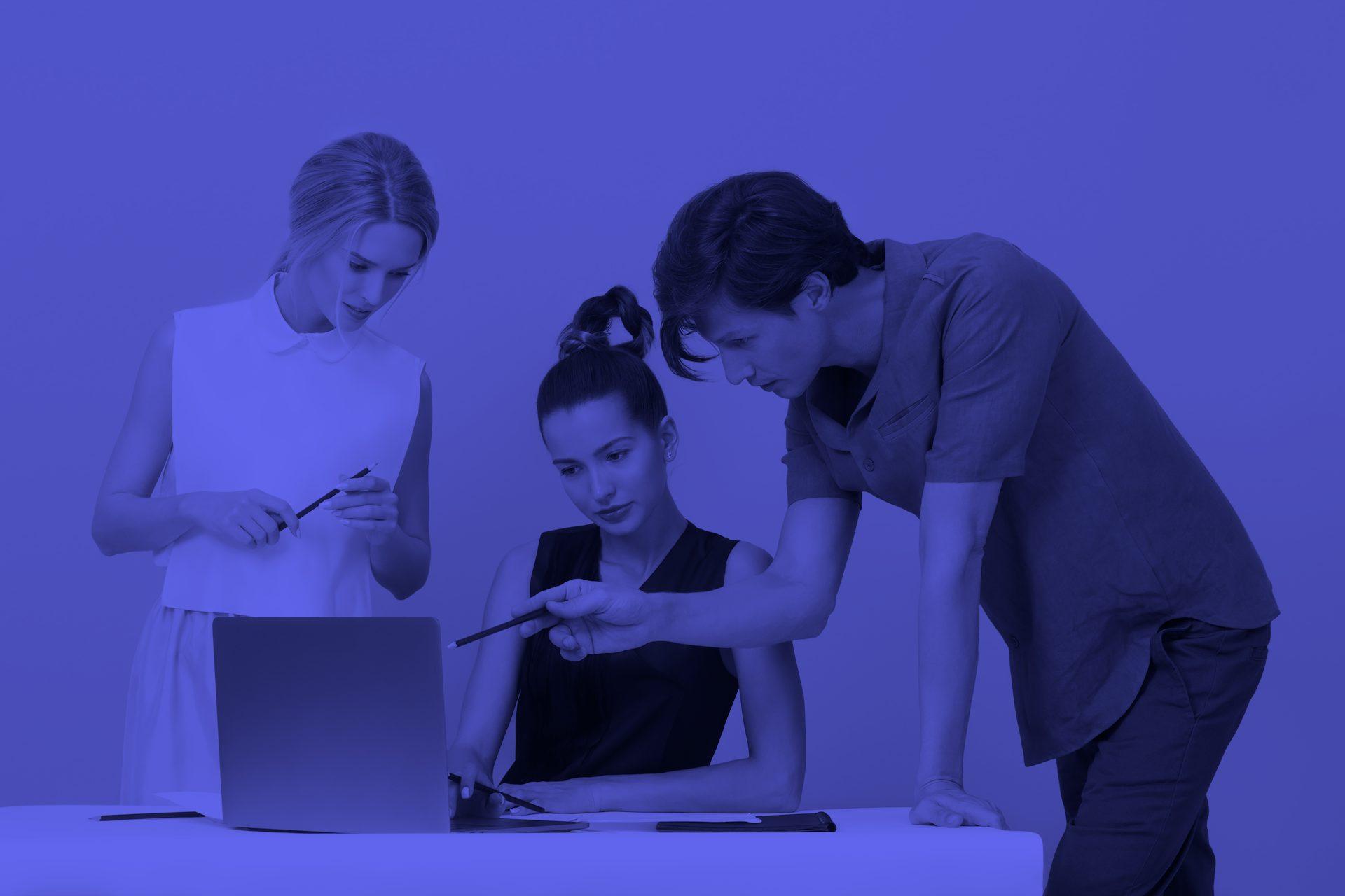 Three people working together looking at information on a laptop screen