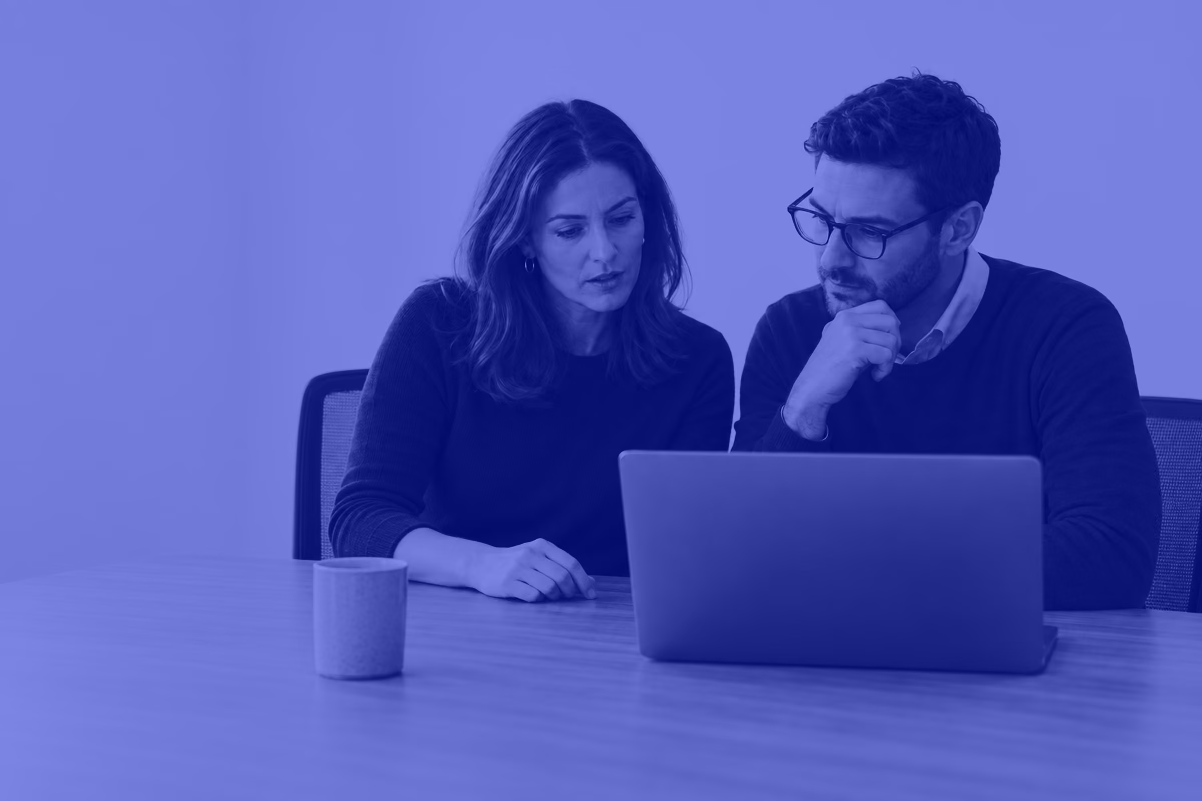 Two colleagues coordinating work around a laptop