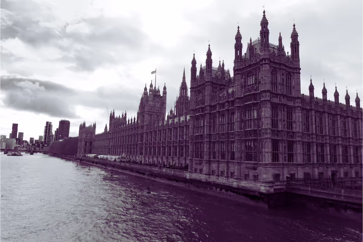 A purple-tinted view of the Palace of Westminster beside the River Thames under a cloudy sky