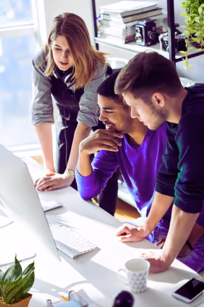 Three colleagues reviewing information together at a laptop